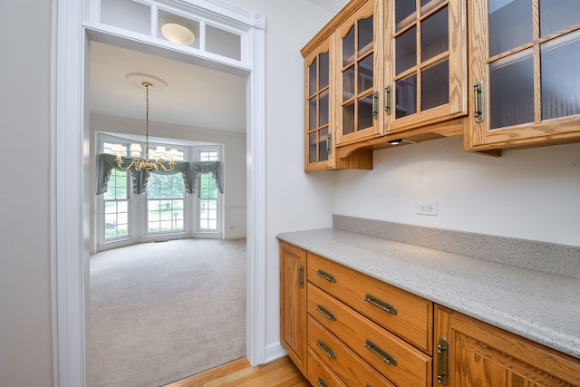 802 Ridgelawn Trl, Batavia, IL 60510 - kitchen featuring brown cabinetry, a chandelier, and light stone counters