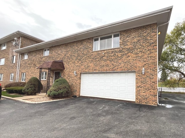 view of front of property featuring aphalt driveway, brick siding, and a garage