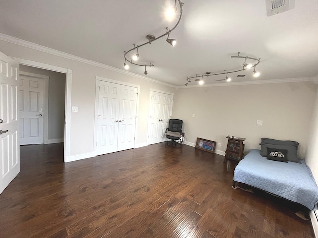 interior space featuring crown molding, wood finished floors, rail lighting, baseboards, and visible vents