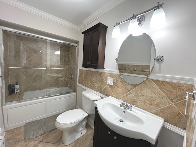 bathroom with bath / shower combo with glass door, toilet, tile walls, crown molding, and vanity