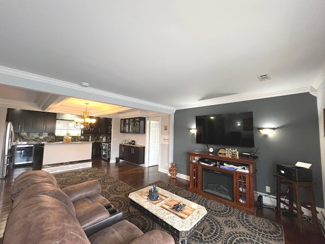 living area featuring dark wood-type flooring, baseboards, a notable chandelier, and ornamental molding
