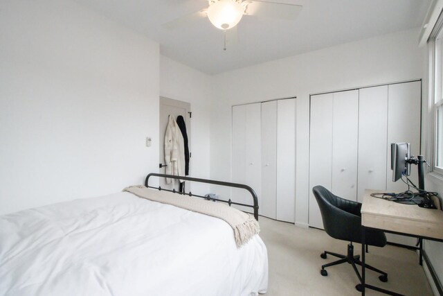 bedroom featuring ceiling fan, two closets, and light colored carpet