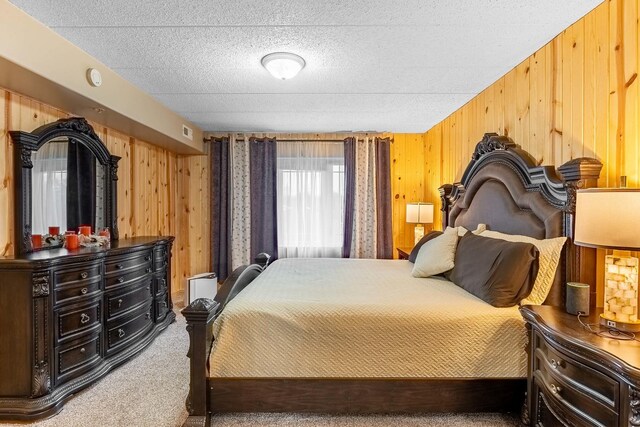 carpeted bedroom featuring a textured ceiling, wood walls, and visible vents