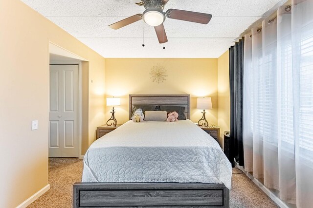 bedroom with ceiling fan, baseboards, and light carpet