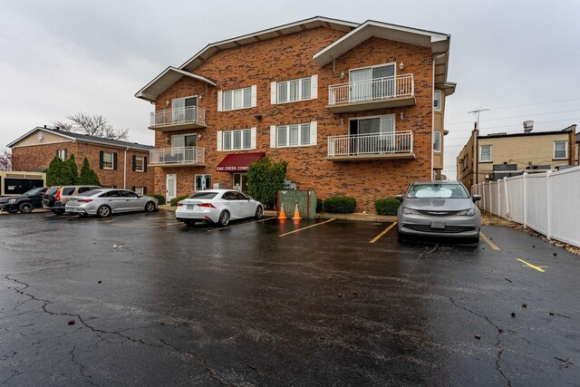 view of property with fence and uncovered parking