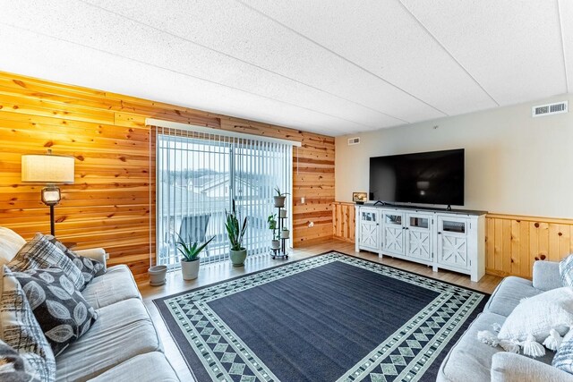living area featuring visible vents, wood finished floors, wooden walls, and a textured ceiling