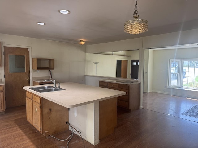 kitchen featuring a sink, dark wood finished floors, a center island with sink, and light countertops