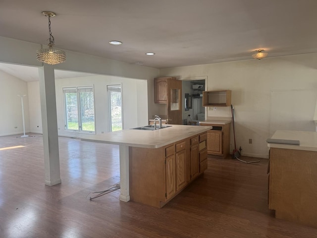 kitchen featuring dark wood-style flooring, baseboards, an island with sink, light countertops, and a sink