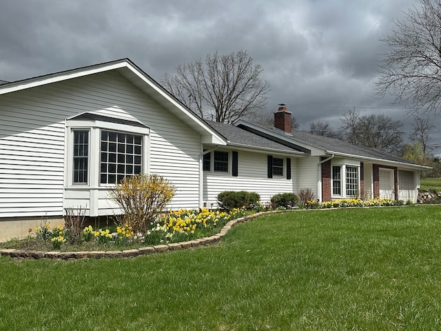 view of side of home featuring a lawn, a chimney, and a shingled roof