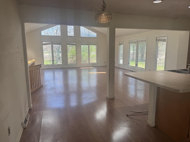 unfurnished living room with a sink, visible vents, wood finished floors, and lofted ceiling