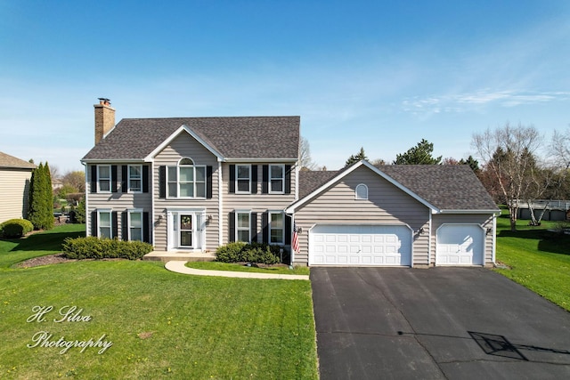 colonial inspired home featuring a garage, a front yard, a chimney, asphalt driveway, and a shingled roof