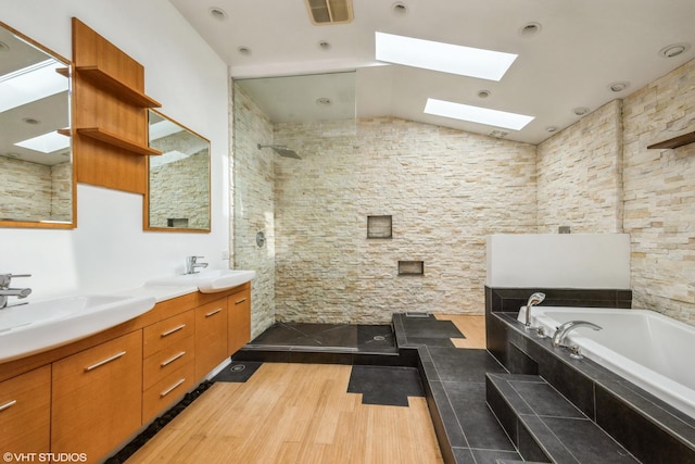 full bathroom with a sink, a walk in shower, lofted ceiling with skylight, and wood finished floors