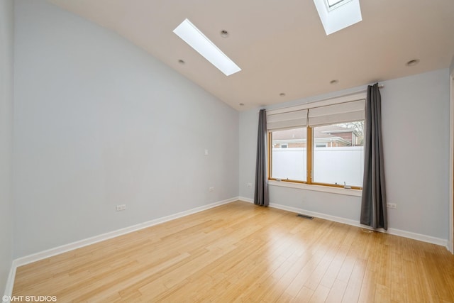 unfurnished room with light wood-type flooring, baseboards, vaulted ceiling with skylight, and visible vents