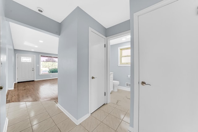 corridor with visible vents, baseboards, and light tile patterned floors