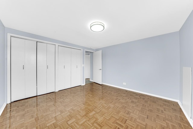 unfurnished bedroom featuring multiple closets and baseboards