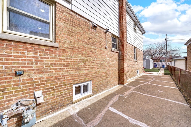 view of home's exterior with brick siding and fence