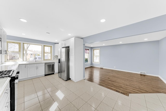 kitchen featuring a sink, open floor plan, appliances with stainless steel finishes, light countertops, and light tile patterned floors