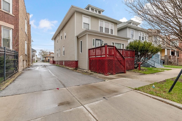 view of front of home featuring fence, a residential view, and a wooden deck