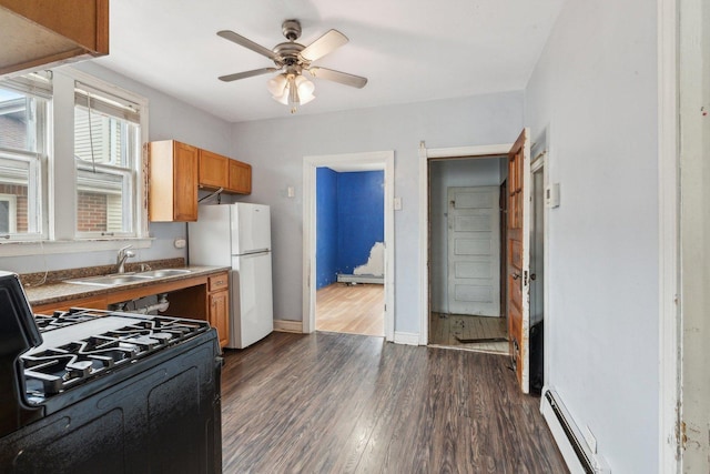 kitchen featuring a sink, freestanding refrigerator, black range with gas cooktop, brown cabinetry, and dark wood-style flooring