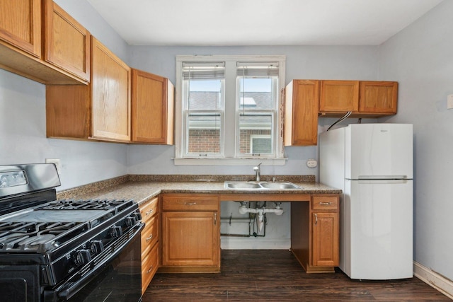 kitchen with gas stove, freestanding refrigerator, dark wood-style flooring, a sink, and brown cabinets