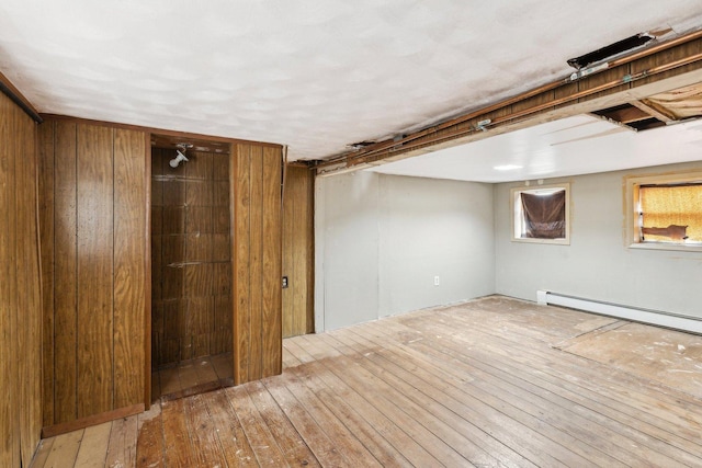 basement featuring hardwood / wood-style flooring and a baseboard heating unit