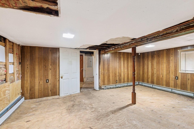 finished below grade area featuring baseboard heating and wooden walls