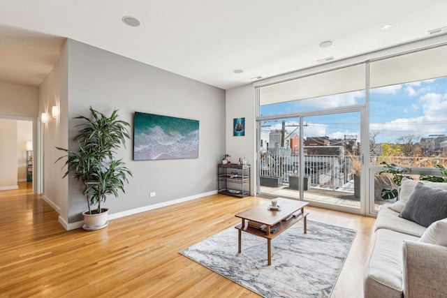 living room featuring baseboards, wood finished floors, and floor to ceiling windows