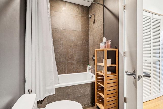 bathroom featuring toilet, wood finished floors, and tiled shower / bath