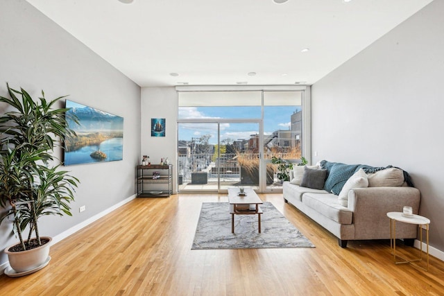 living area featuring expansive windows, baseboards, and wood finished floors