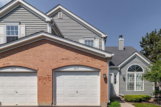 view of front of house featuring brick siding, a chimney, and driveway