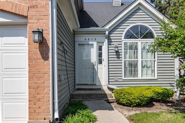 doorway to property with brick siding and a garage