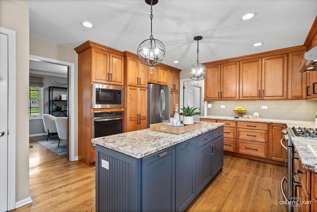 kitchen with light wood-style floors, a kitchen island, stainless steel appliances, and tasteful backsplash