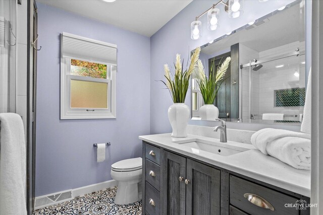 full bath with visible vents, baseboards, vanity, toilet, and tiled shower