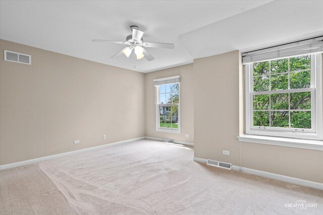 carpeted empty room with visible vents, baseboards, and ceiling fan