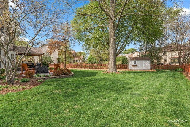 view of yard with a storage unit, a fenced backyard, an outbuilding, and a patio