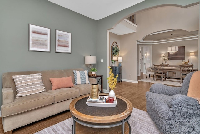living room with baseboards, arched walkways, and wood finished floors