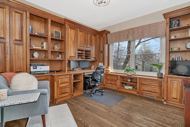 office area with visible vents, built in desk, and dark wood finished floors