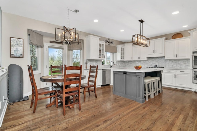 kitchen with decorative backsplash, appliances with stainless steel finishes, light countertops, white cabinetry, and a notable chandelier