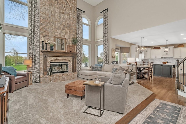 living area featuring a towering ceiling, wood finished floors, a chandelier, and a fireplace