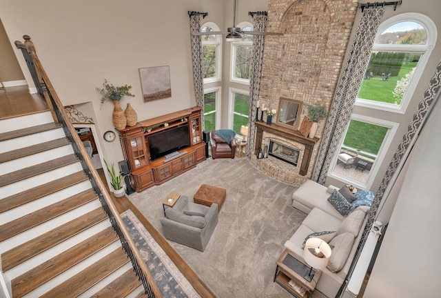 living area with a towering ceiling, stairs, and a fireplace