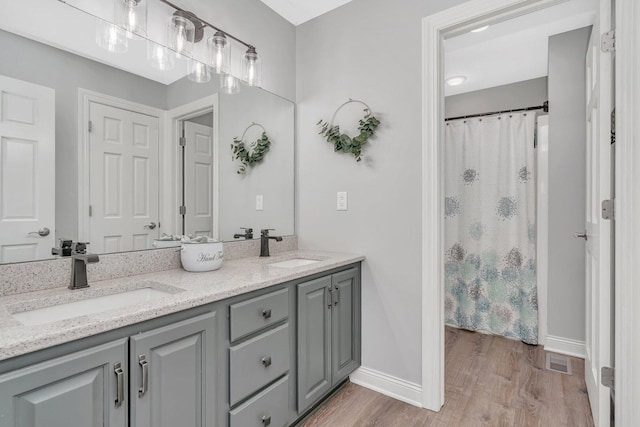 full bath with baseboards, visible vents, wood finished floors, and a sink