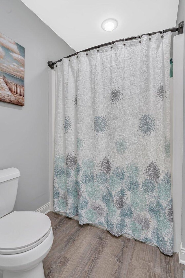 full bathroom featuring toilet, a shower with curtain, wood finished floors, and baseboards