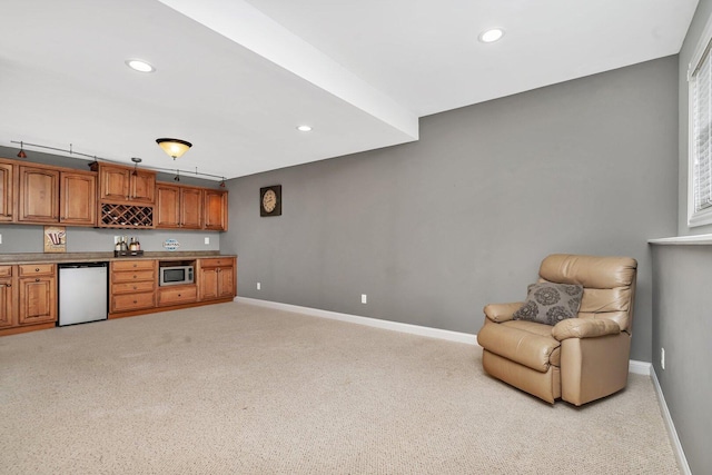 kitchen featuring baseboards, dishwashing machine, light colored carpet, and brown cabinets