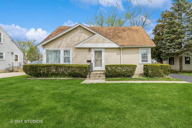 bungalow-style home featuring roof with shingles, entry steps, and a front lawn
