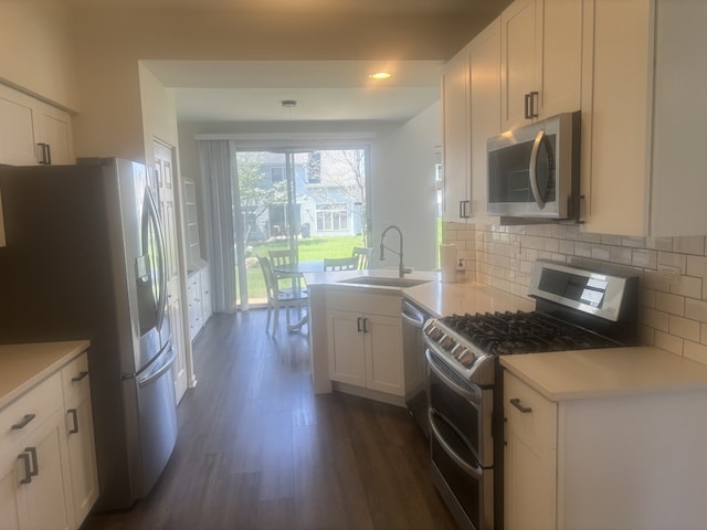 kitchen with a sink, dark wood-type flooring, backsplash, white cabinets, and appliances with stainless steel finishes
