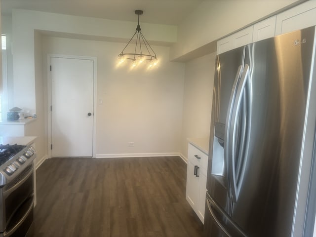 unfurnished dining area with an inviting chandelier, dark wood-style flooring, and baseboards