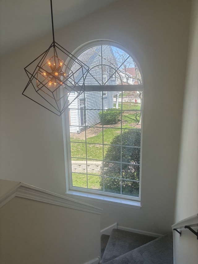 stairway featuring an inviting chandelier, baseboards, and carpet floors
