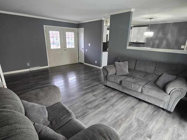living area with wood finished floors, visible vents, baseboards, and ornamental molding