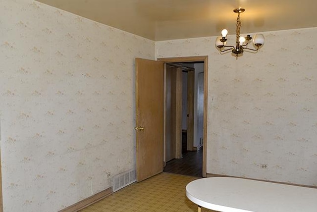 unfurnished room with a chandelier and wallpapered walls