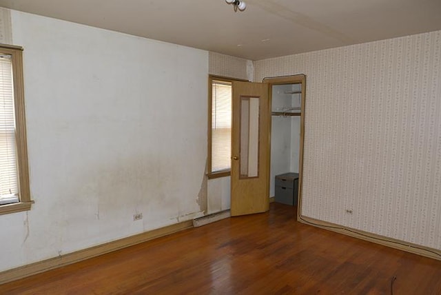 spare room featuring wood finished floors, wallpapered walls, and a baseboard radiator